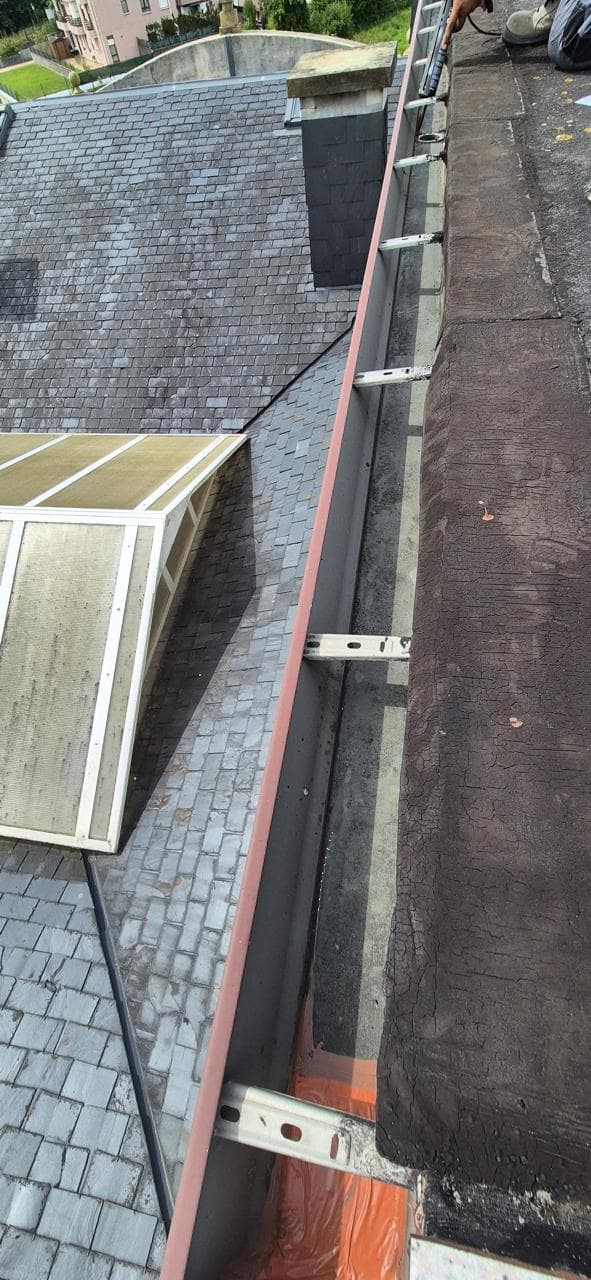 Operario sellando junta de canalones con silicona